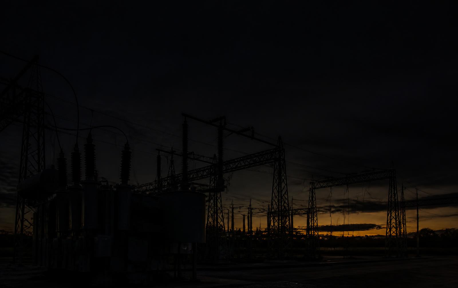High voltage substation silhouetted against a dusk sky